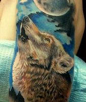 wilk wyje do księżyca, tatuaż na ramieniu