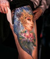 kwiatek i twarz kobiety tatuaż na udzie
