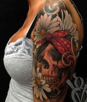 kwiaty stokrotki i czaszka tatuaż na ramieniu