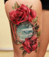 czerwone róże i zegar w środku - tatuaż na udzie