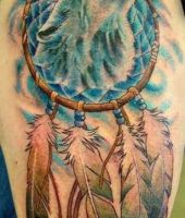 wilk i łapacz snów tatuaż na ramieniu